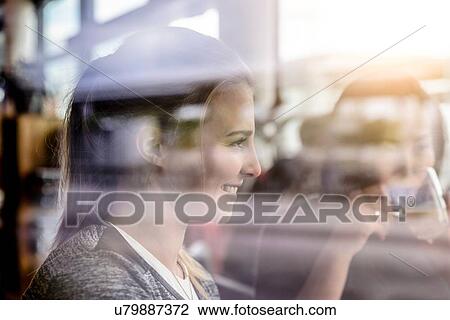 Stock Image - Two female students having coffee in cafe window seat. Fotosearch