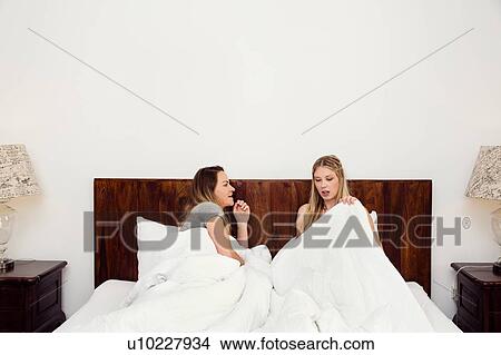 Two women sitting up in bed chatting View Large Photo Image Picture - Two women sitting up in bed chatting. Fotosearch