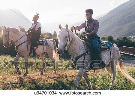 Two young men horse riding in field, Primaluna, Trentino-Alto Adige, Italy View Large Photo Image Picture - Two young men horse riding in field, Primaluna, Trentino-Alto Adige, Italy. Fotosearch