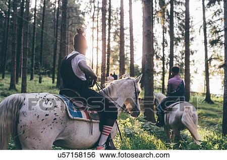 Two young men horse riding in sunlit forest, Primaluna, Trentino-Alto Adige, Italy View Large Photo Image Stock Photograph - Two young men horse riding in sunlit forest, Primaluna, Trentino-Alto Adige, Italy. Fotosearch