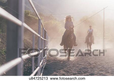 Two young women riding horses in dusty equestrian arena View Large Photo Image Stock Image - Two young women riding horses in dusty equestrian arena. Fotosearch