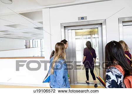 Stock Image - University students entering elevator in campus. Fotosearch