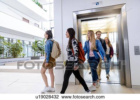 Stock Image - University students exiting elevator in campus. Fotosearch