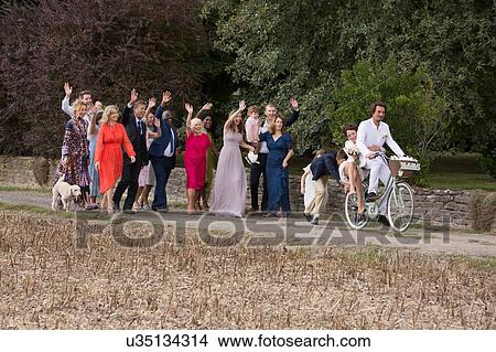 Wedding guests waving off newlyweds on bicycles View Large Photo Image Picture - Wedding guests waving off newlyweds on bicycles. Fotosearch