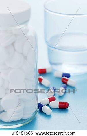 White pills in a glass bottle and a glass of water with various other drug capsules in the background. View Large Photo Image Stock Photograph - White pills in a glass bottle and a glass of water with various other drug capsules in the background.. Fotosearch