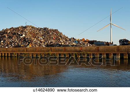 Stock Image - Wind turbine located near metal scrapyard. Fotosearch