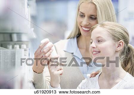 Stock Image - Woman and girl reading label in pharmacy.. Fotosearch