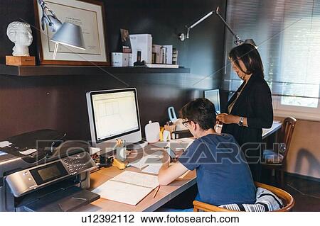 Stock Image - Woman and son working in home office. Fotosearch