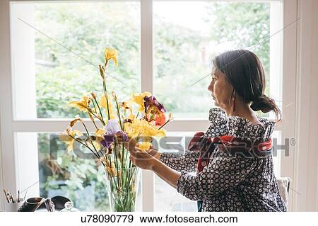 Stock Photo - Woman arranging flowers in vase. Fotosearch