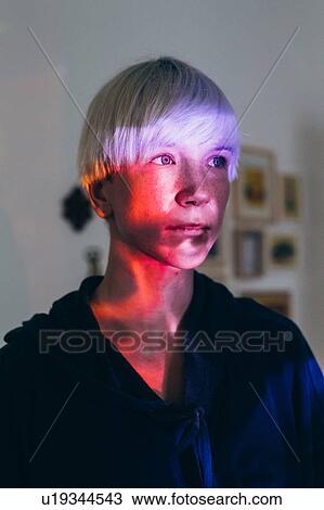 Stock Image - Woman daydreaming, red light reflected on face. Fotosearch
