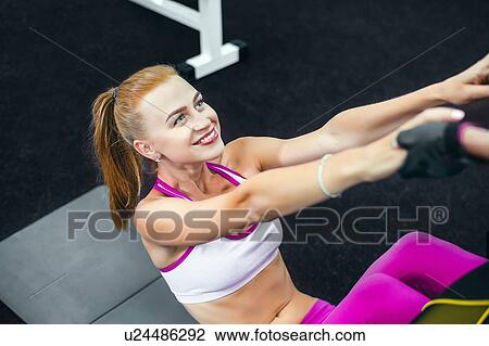 Stock Image - Woman doing sit ups in gym and smiling. Fotosearch