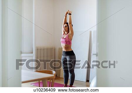 Stock Photo - Woman doing stretching exercise at home. Fotosearch