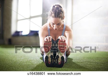 Stock Image - Woman doing stretching exercise in gym. Fotosearch