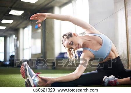 Stock Photo - Woman doing stretching exercise in gym. Fotosearch