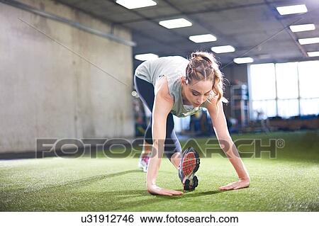 Stock Photograph - Woman doing stretching exercise in gym. Fotosearch