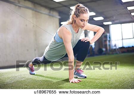 Stock Photography - Woman doing stretching exercise in gym. Fotosearch