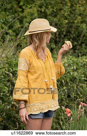 Stock Photo - Woman eating apple from garden. Fotosearch