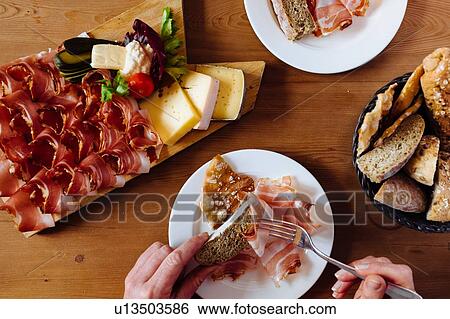 Woman eating variety of bread, cheese and parma ham at table, overhead close up of hands View Large Photo Image Stock Photograph - Woman eating variety of bread, cheese and parma ham at table, overhead close up of hands. Fotosearch