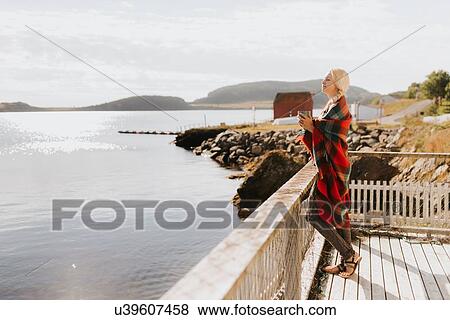 Stock Photo - Woman enjoying morning drink on balcony by sea, Halifax, Canada. Fotosearch