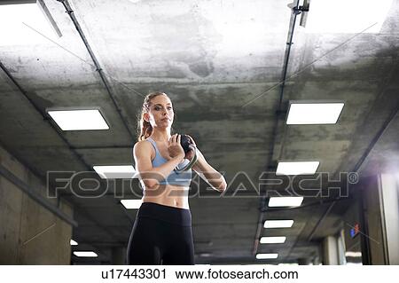 Stock Image - Woman exercising with kettlebell in gym. Fotosearch