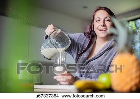 Picture - Woman having smoothie for breakfast at home. Fotosearch