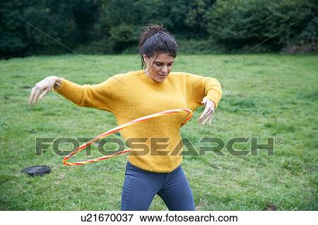 Woman hula hooping in field View Large Photo Image Stock Photo - Woman hula hooping in field. Fotosearch