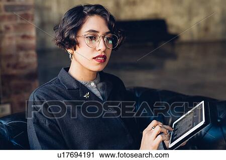 Woman in armchair using digital tablet View Large Photo Image Stock Image - Woman in armchair using digital tablet. Fotosearch