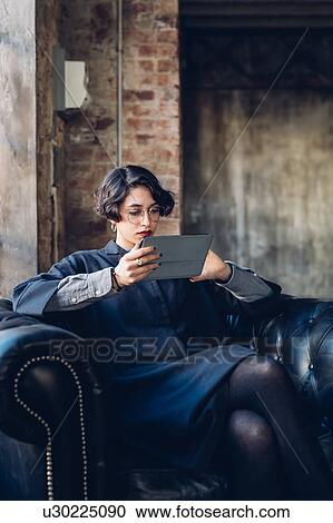 Woman in armchair using digital tablet View Large Photo Image Stock Image - Woman in armchair using digital tablet. Fotosearch