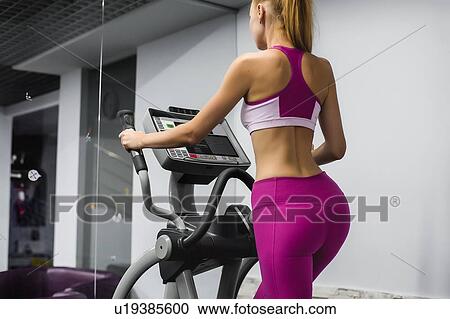 Woman in gym using exercise equipment View Large Photo Image Stock Image - Woman in gym using exercise equipment. Fotosearch