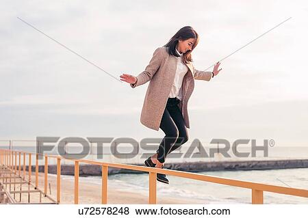 Woman jumping off handrail on beach View Large Photo Image Stock Photo - Woman jumping off handrail on beach. Fotosearch
