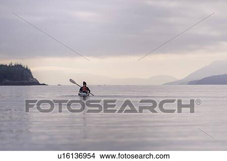 Picture - Woman kayaking in lake, Johnstone Strait, Telegraph Cove, Canada. Fotosearch