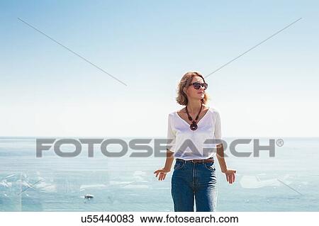 Woman leaning against glass balcony on seaside terrace View Large Photo Image Stock Image - Woman leaning against glass balcony on seaside terrace. Fotosearch