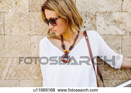 Stock Photo - Woman leaning against stone wall. Fotosearch