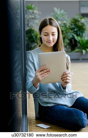 Woman leaning on glass wall using digital tablet View Large Photo Image Stock Image - Woman leaning on glass wall using digital tablet. Fotosearch