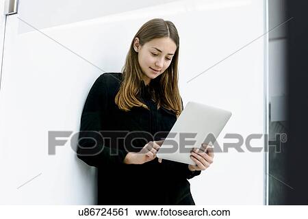 Woman leaning on wall using digital tablet View Large Photo Image Stock Image - Woman leaning on wall using digital tablet. Fotosearch