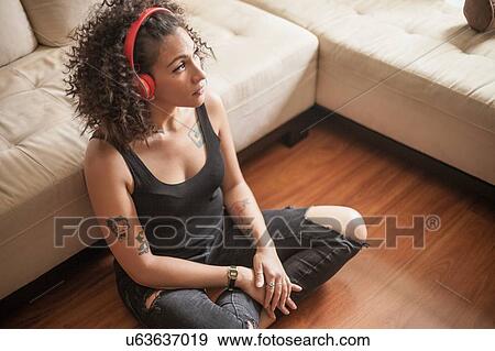Stock Photo - Woman listening to music and daydreaming at home. Fotosearch