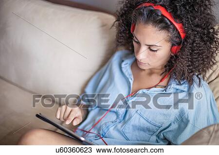 Woman listening to music on digital tablet at home View Large Photo Image Stock Image - Woman listening to music on digital tablet at home. Fotosearch