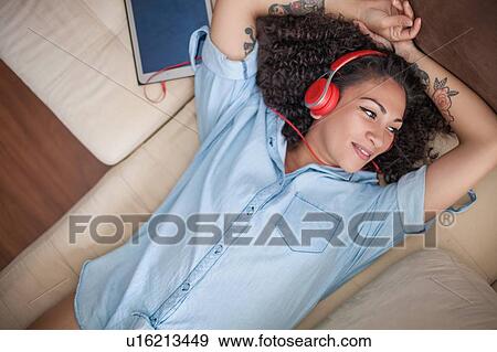 Stock Photo - Woman listening to music on digital tablet at home. Fotosearch