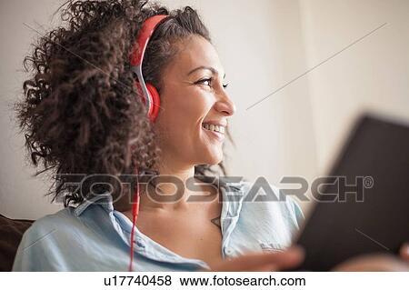 Stock Photo - Woman listening to music on digital tablet at home. Fotosearch