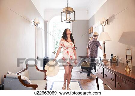 Woman looking up at hotel lobby lampshade, boyfriend carrying suitcase View Large Photo Image Stock Photo - Woman looking up at hotel lobby lampshade, boyfriend carrying suitcase. Fotosearch