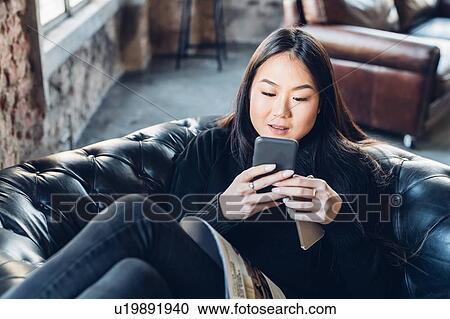 Woman on armchair using smartphone View Large Photo Image Stock Image - Woman on armchair using smartphone. Fotosearch