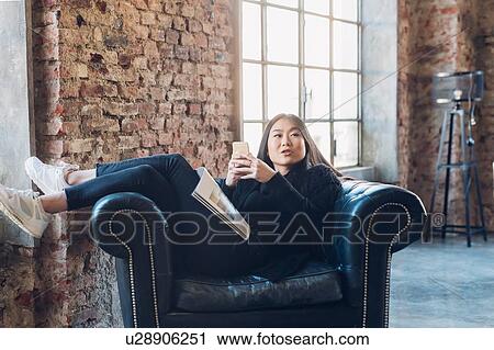 Woman on armchair using smartphone View Large Photo Image Stock Image - Woman on armchair using smartphone. Fotosearch