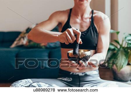 Stock Photo - Woman playing singing bowl at home. Fotosearch