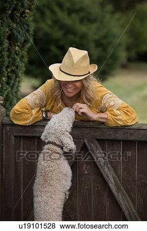 Stock Photo - Woman playing with pet dog in garden. Fotosearch