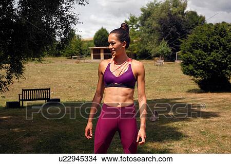 Picture - Woman practicing yoga in garden, looking sideways. Fotosearch