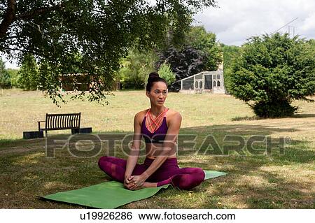 Woman practicing yoga in garden, taking a break on yoga mat View Large Photo Image Stock Photograph - Woman practicing yoga in garden, taking a break on yoga mat. Fotosearch