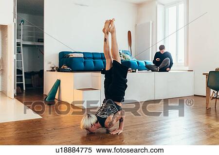 Woman practising yoga at home, friend in background View Large Photo Image Stock Photography - Woman practising yoga at home, friend in background. Fotosearch