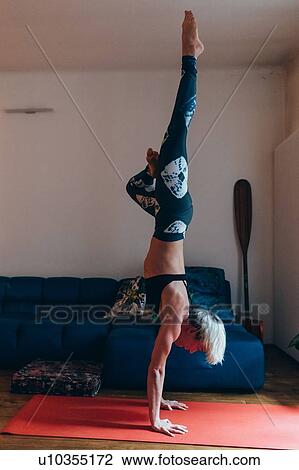 Stock Image - Woman practising yoga at home. Fotosearch