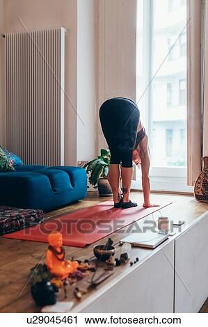 Stock Image - Woman practising yoga at home. Fotosearch