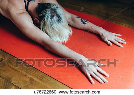 Stock Image - Woman practising yoga at home. Fotosearch